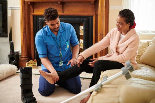 Fisioterapeuta asistiendo a paciente en casa para rehabilitación de lesión en Madrid.