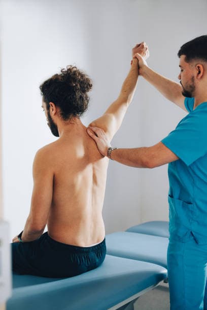 Fisioterapeuta evaluando hombro de paciente en sesión de fisioterapia en Alcobendas